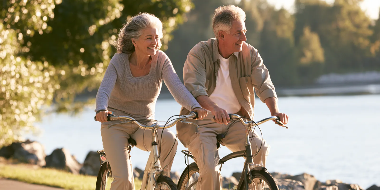 Couple in their 50s riding bicycles side by side along a riverside park path, enjoying life after an avant lending debt payoff plan