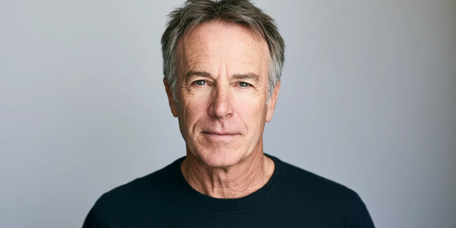 Studio portrait of a man in his fifties with an open, honest expression looking straight at the camera