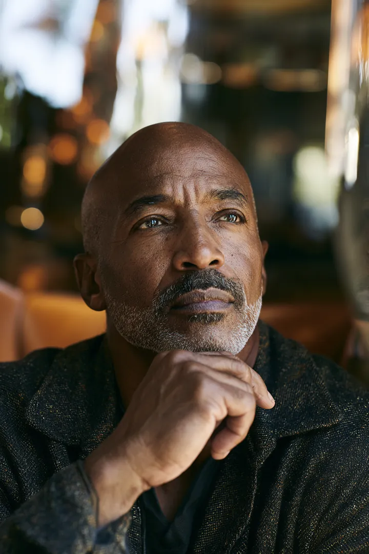Man in his 50s sitting by a cafe window with a thoughtful expression, thinking over personal loan offers before choosing one